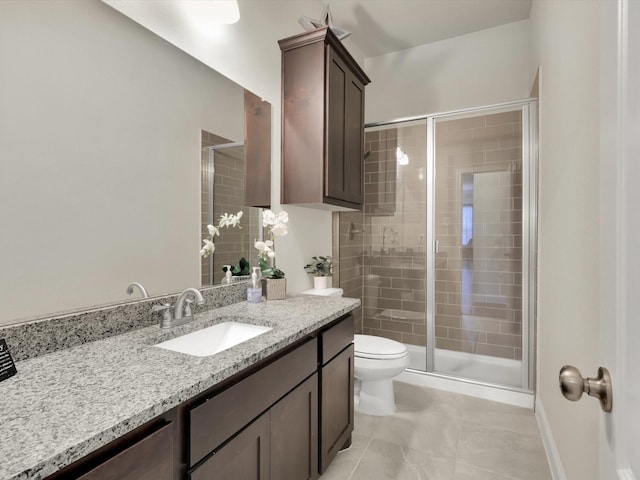 bathroom featuring toilet, vanity, tile patterned floors, and a shower with door