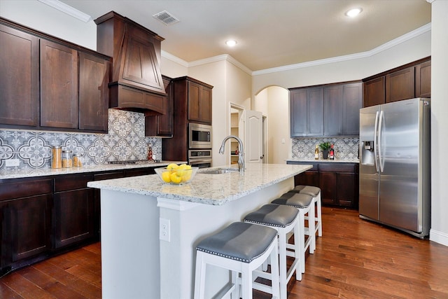 kitchen featuring dark hardwood / wood-style flooring, sink, a center island with sink, and appliances with stainless steel finishes