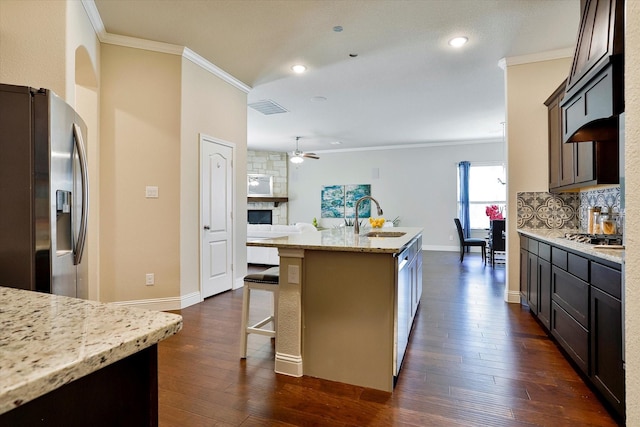 kitchen featuring light stone countertops, sink, stainless steel appliances, dark hardwood / wood-style flooring, and a center island with sink