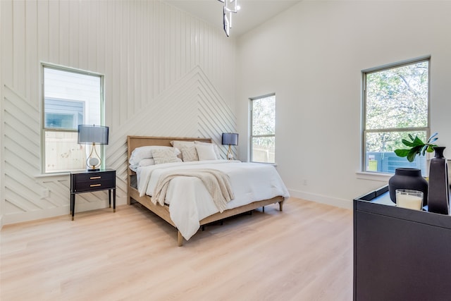 bedroom featuring multiple windows, hardwood / wood-style flooring, and a high ceiling