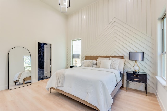 bedroom featuring a towering ceiling and light hardwood / wood-style flooring