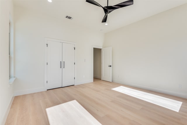 unfurnished bedroom with ceiling fan, light wood-type flooring, and a closet