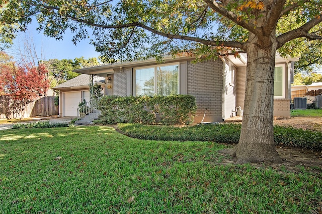 view of front of property with a front yard, a garage, and central air condition unit