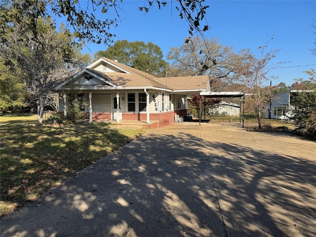 view of front of house with a carport, covered porch, and a front lawn