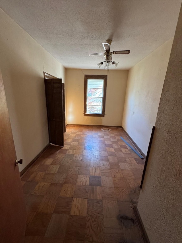 empty room featuring ceiling fan, a textured ceiling, and parquet flooring