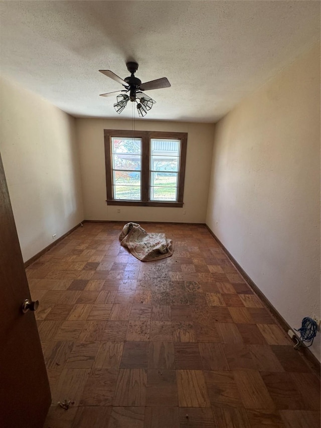 empty room featuring ceiling fan, dark parquet flooring, and a textured ceiling