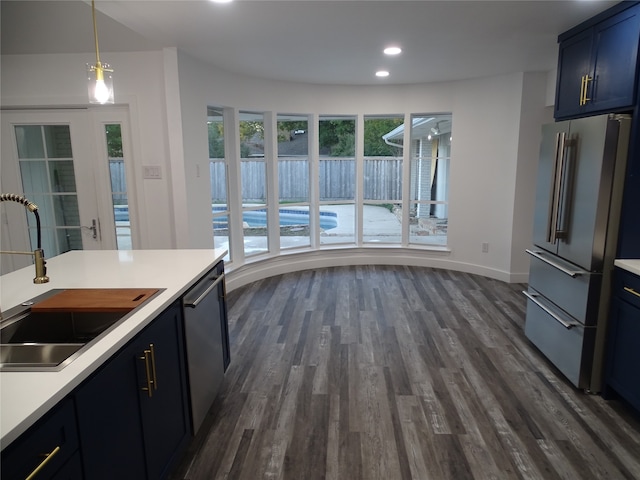 kitchen featuring sink, dark hardwood / wood-style floors, blue cabinets, decorative light fixtures, and appliances with stainless steel finishes