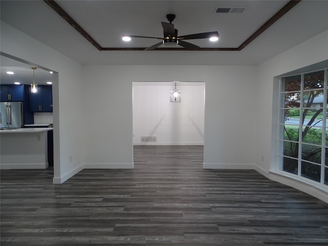 unfurnished living room with a raised ceiling, ceiling fan, and dark wood-type flooring