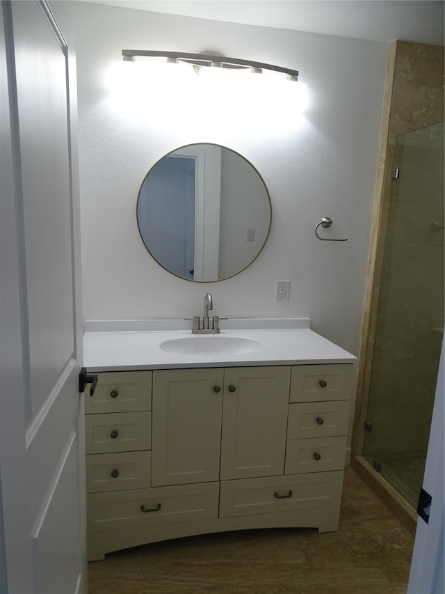 bathroom featuring a shower with door and vanity