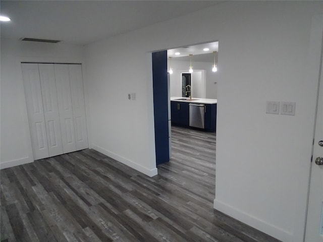 unfurnished bedroom featuring a closet, dark hardwood / wood-style flooring, ensuite bathroom, and sink