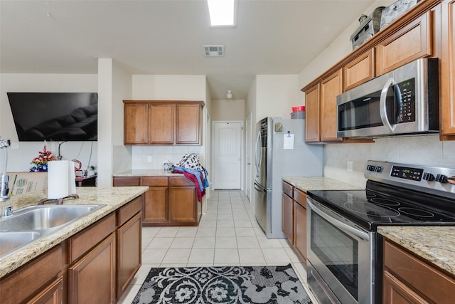 kitchen featuring decorative backsplash, light stone counters, light tile patterned floors, and stainless steel appliances