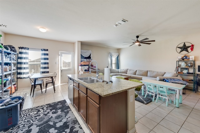 kitchen with a center island with sink, sink, stainless steel dishwasher, ceiling fan, and light tile patterned floors