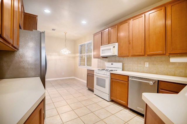 kitchen featuring decorative backsplash, pendant lighting, stainless steel appliances, and light tile patterned floors