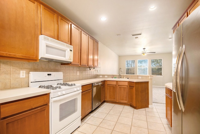 kitchen with sink, ceiling fan, light tile patterned floors, appliances with stainless steel finishes, and kitchen peninsula