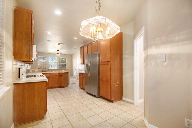 kitchen with decorative light fixtures, white appliances, decorative backsplash, light tile patterned floors, and ceiling fan with notable chandelier