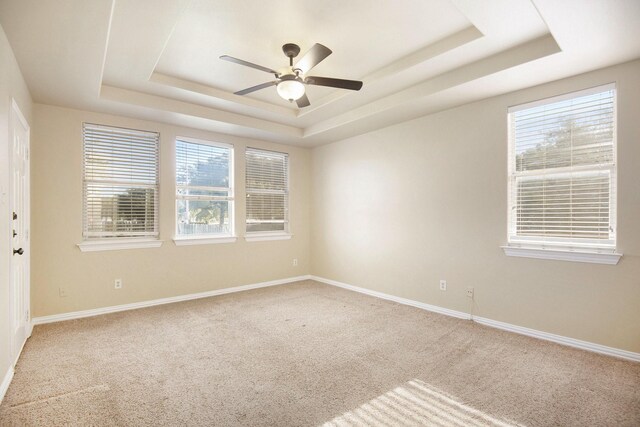 carpeted empty room with a raised ceiling and ceiling fan