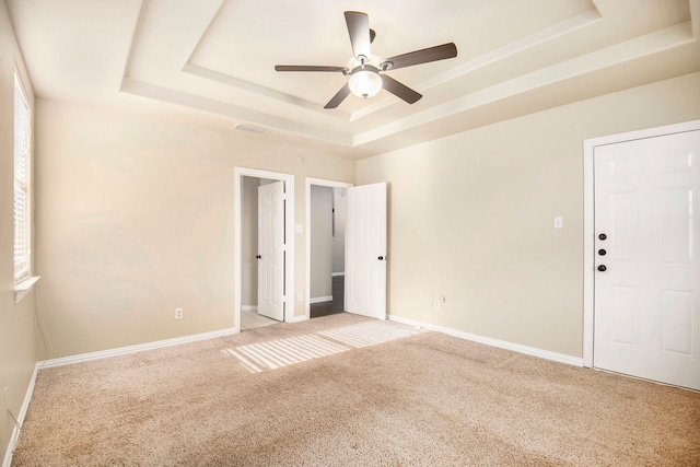 empty room featuring a tray ceiling, ceiling fan, and light colored carpet