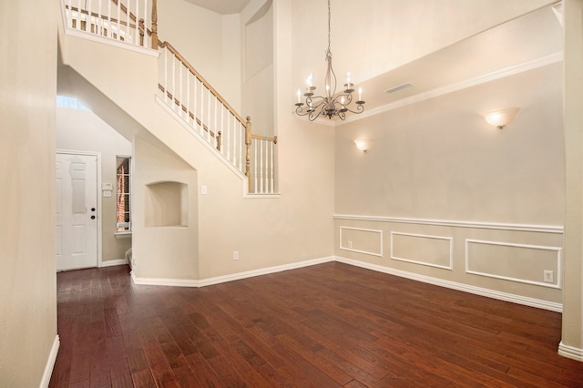 unfurnished room with a towering ceiling, a chandelier, and dark hardwood / wood-style floors