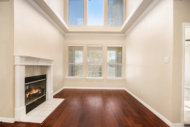 unfurnished living room featuring a tile fireplace, hardwood / wood-style flooring, and crown molding