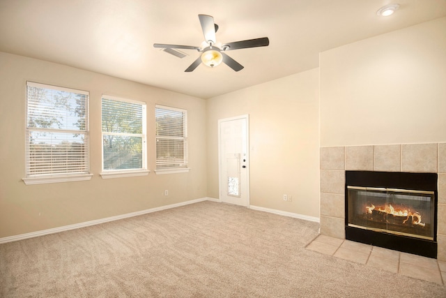 unfurnished living room with a tile fireplace, light carpet, and ceiling fan