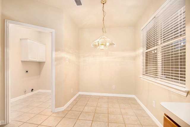 unfurnished dining area featuring light tile patterned floors and a chandelier