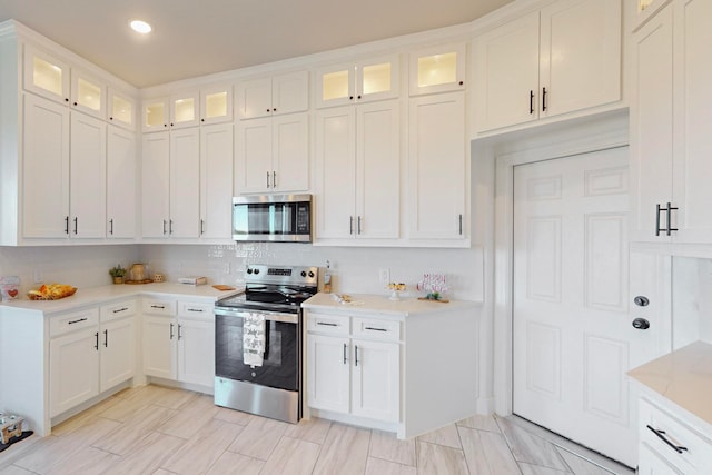 kitchen featuring white cabinets, backsplash, and appliances with stainless steel finishes