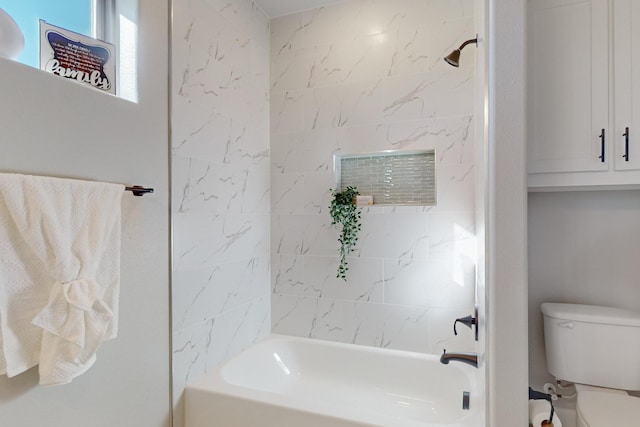 bathroom featuring toilet and tiled shower / bath