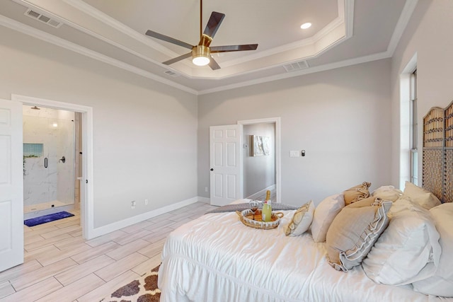 bedroom with ensuite bathroom, ceiling fan, light wood-type flooring, ornamental molding, and a tray ceiling