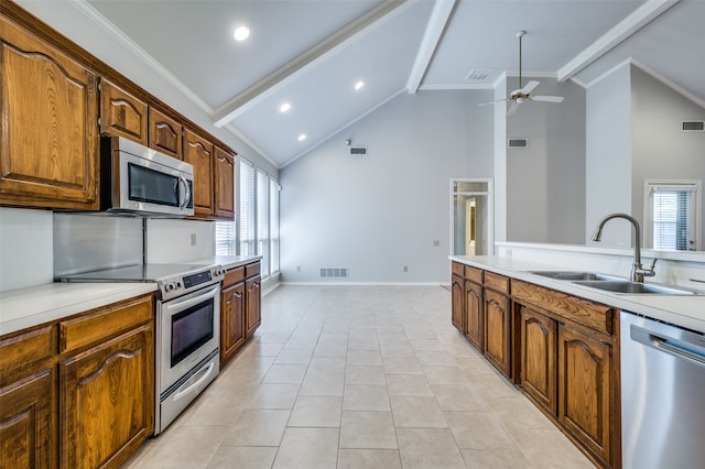 kitchen with appliances with stainless steel finishes, sink, a healthy amount of sunlight, and beam ceiling