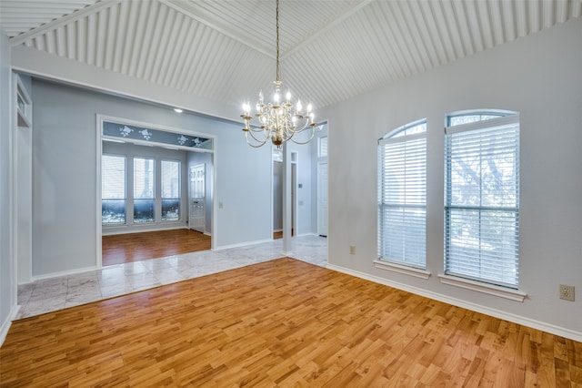 unfurnished room featuring a wealth of natural light, light hardwood / wood-style flooring, lofted ceiling, and an inviting chandelier