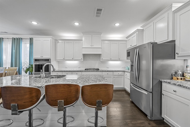 kitchen with light stone countertops, dark hardwood / wood-style flooring, white cabinets, and appliances with stainless steel finishes