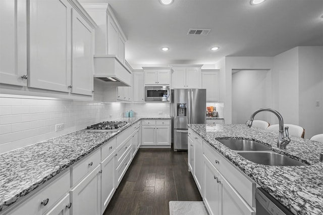 kitchen with appliances with stainless steel finishes, light stone counters, sink, dark hardwood / wood-style floors, and white cabinetry