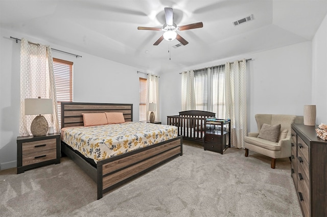 bedroom with multiple windows, ceiling fan, and light colored carpet