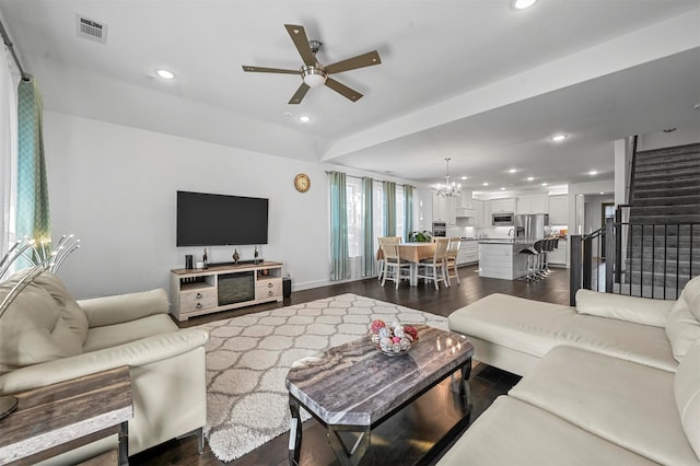 living room with ceiling fan with notable chandelier and dark hardwood / wood-style flooring