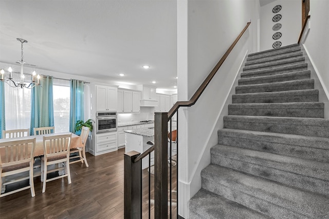 stairs with hardwood / wood-style floors and a notable chandelier