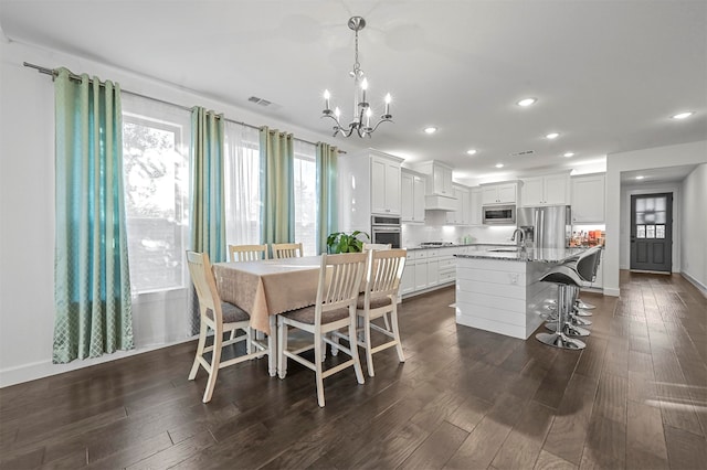 dining room with sink, dark hardwood / wood-style floors, and an inviting chandelier