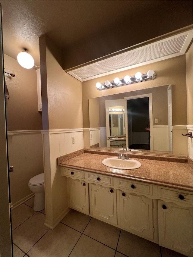 bathroom with tile patterned flooring, a textured ceiling, vanity, and toilet