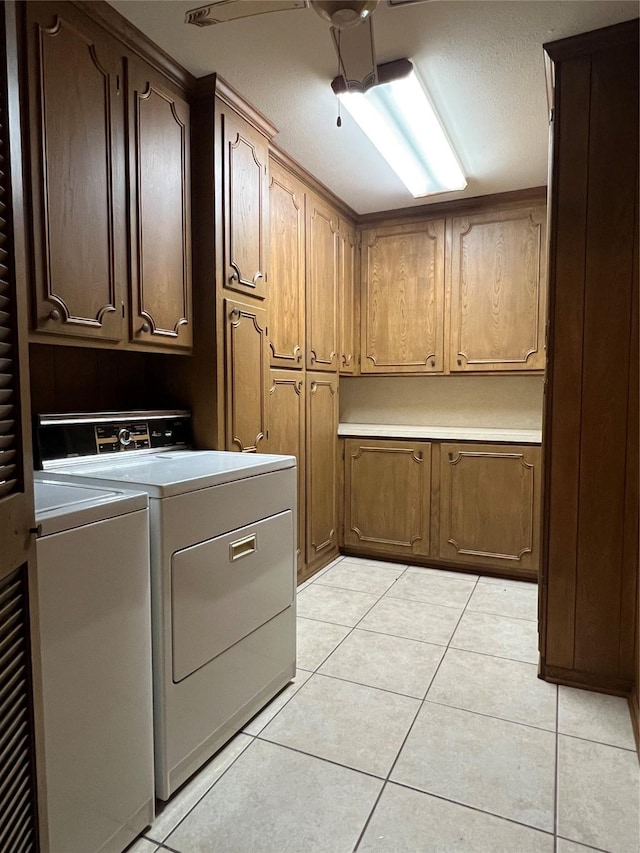 laundry room with cabinets, washer and clothes dryer, and light tile patterned flooring