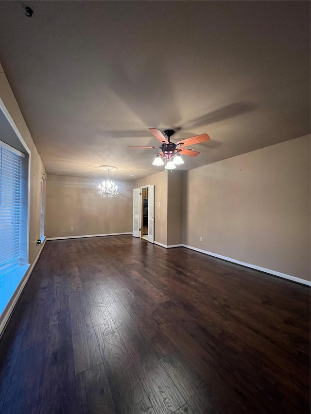 spare room with dark hardwood / wood-style flooring and ceiling fan with notable chandelier