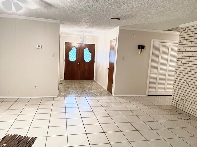 tiled entrance foyer with crown molding, ceiling fan with notable chandelier, and a textured ceiling