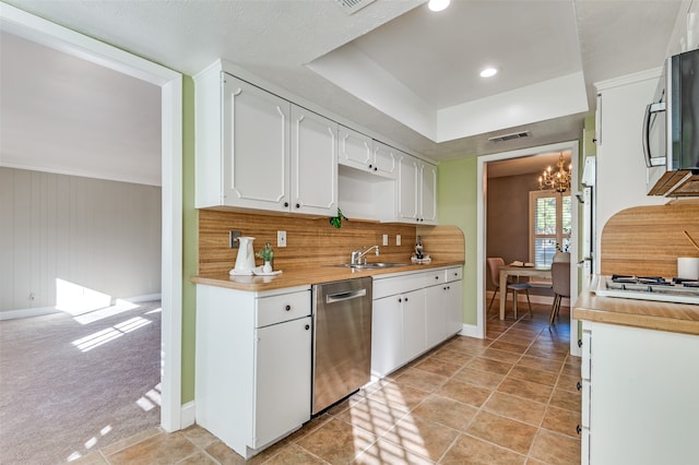 kitchen with backsplash, a chandelier, light colored carpet, white cabinets, and appliances with stainless steel finishes