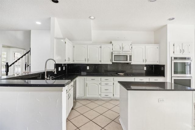 kitchen featuring white cabinetry, sink, stainless steel appliances, tasteful backsplash, and light tile patterned floors