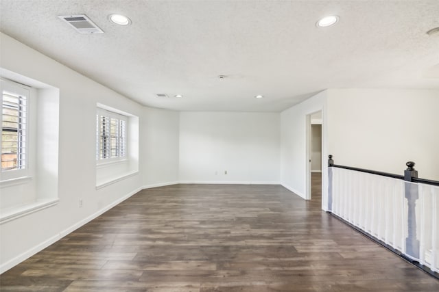 empty room with a textured ceiling and dark hardwood / wood-style floors