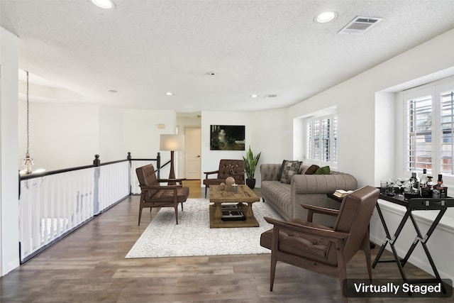 living room with a textured ceiling and dark hardwood / wood-style floors