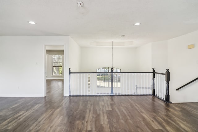 spare room with a textured ceiling, dark hardwood / wood-style floors, and a notable chandelier