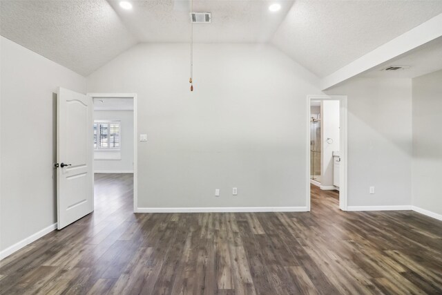 spare room with a textured ceiling, dark hardwood / wood-style flooring, and vaulted ceiling