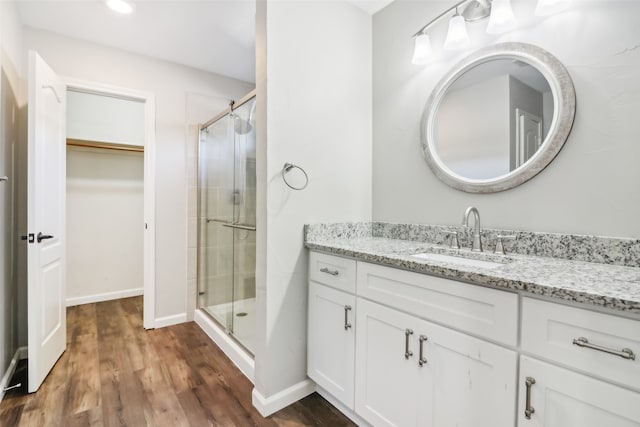 bathroom with hardwood / wood-style flooring, vanity, and a shower with door