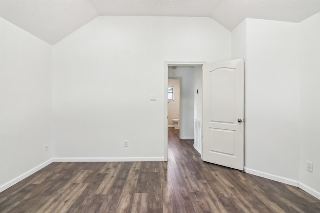 empty room featuring dark wood-type flooring and lofted ceiling