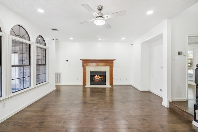 unfurnished living room featuring a fireplace, ceiling fan, dark hardwood / wood-style flooring, and a textured ceiling