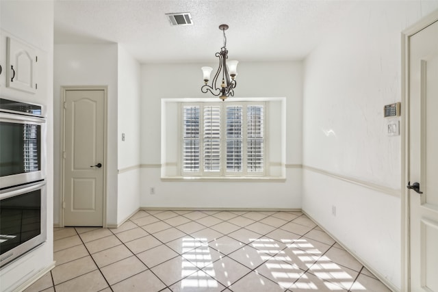 unfurnished dining area featuring a textured ceiling, a notable chandelier, and light tile patterned flooring